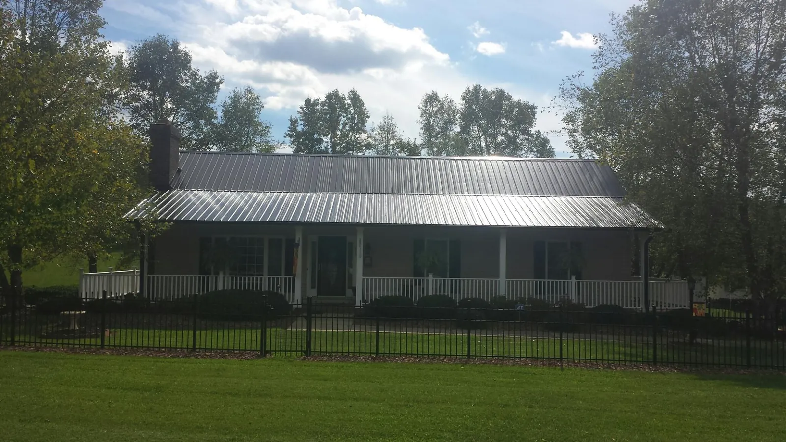 Gray metal roof on a brick ranch with a full width front porch — Gutter Guard Installation work by our crew in Randolph